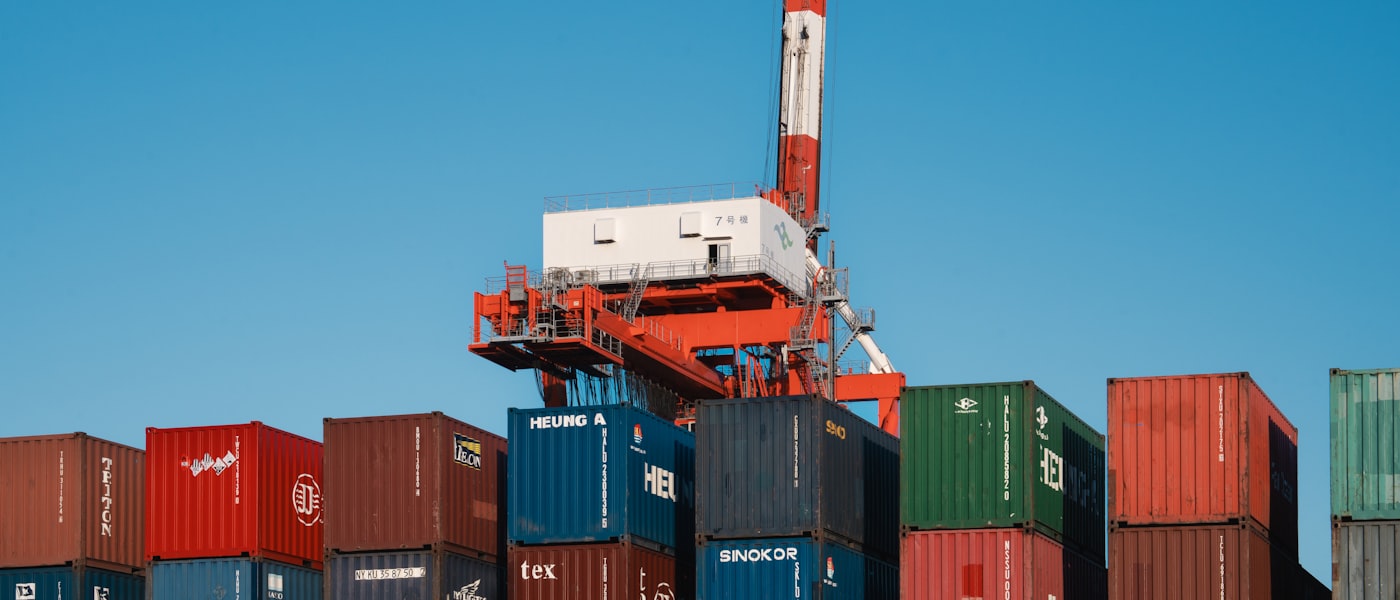 Freight containers stacked at a port terminal beneath a gantry crane